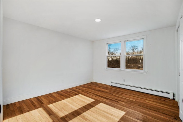 unfurnished room featuring baseboard heating and hardwood / wood-style flooring