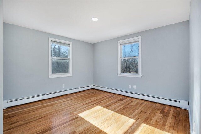 empty room with a baseboard radiator and light hardwood / wood-style flooring