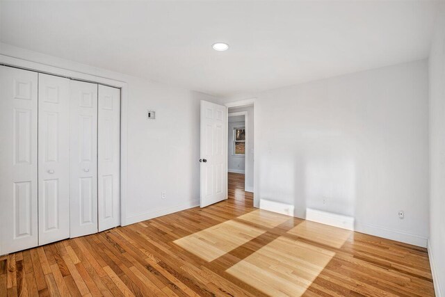 unfurnished bedroom with hardwood / wood-style floors and a closet