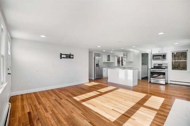 kitchen featuring appliances with stainless steel finishes, a baseboard heating unit, a center island, light hardwood / wood-style floors, and white cabinets