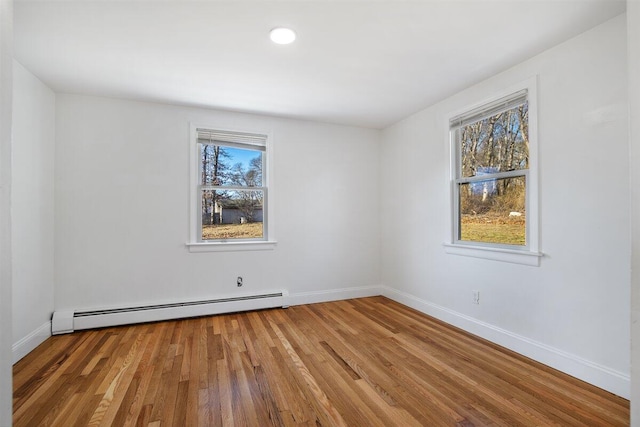 unfurnished room featuring baseboard heating and hardwood / wood-style floors