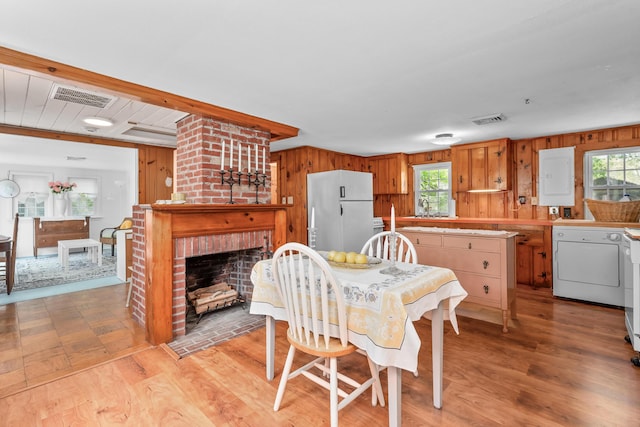 75 Swan Lake Rd, West Yarmouth, MA 02673 - dining room featuring wooden walls, light wood-type flooring, and a brick fireplace
