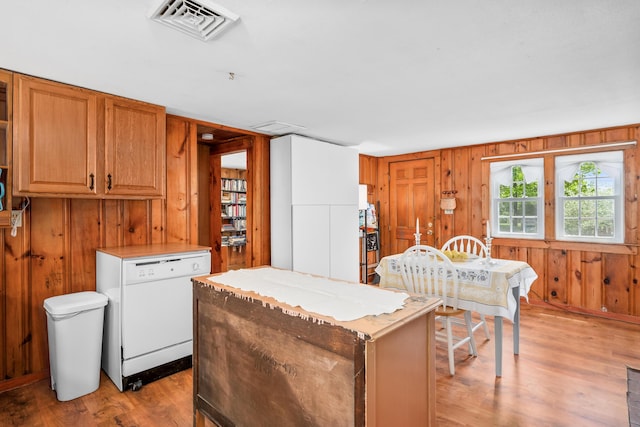 75 Swan Lake Rd, West Yarmouth, MA 02673 - kitchen with dishwasher, light wood-style floors, wood walls, a kitchen island, and light countertops