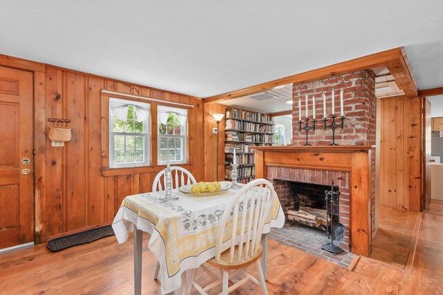 75 Swan Lake Rd, West Yarmouth, MA 02673 - dining room with wood finished floors, wooden walls, and a fireplace