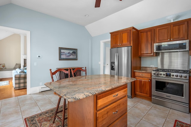 kitchen with a kitchen island, light tile patterned flooring, light stone countertops, and stainless steel appliances