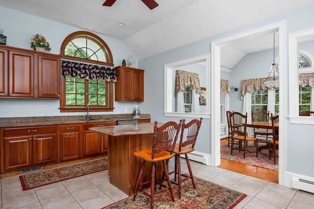 kitchen featuring vaulted ceiling, baseboard heating, light tile patterned floors, and a kitchen island