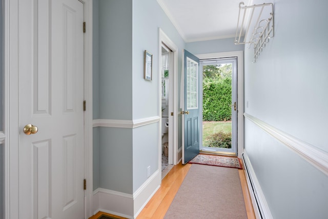 doorway to outside featuring baseboard heating, ornamental molding, and light hardwood / wood-style floors