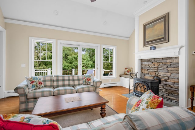 living room featuring a wood stove, a wealth of natural light, a baseboard heating unit, and vaulted ceiling