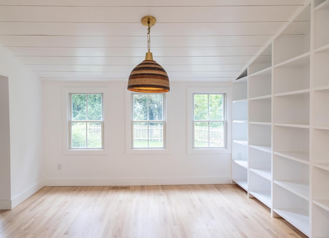 spare room featuring light hardwood / wood-style floors, lofted ceiling, and a healthy amount of sunlight