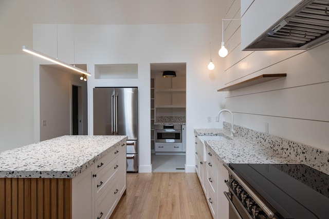 kitchen featuring pendant lighting, white cabinetry, appliances with stainless steel finishes, and custom exhaust hood