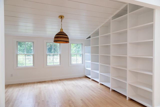 empty room with hardwood / wood-style floors, vaulted ceiling, and a healthy amount of sunlight