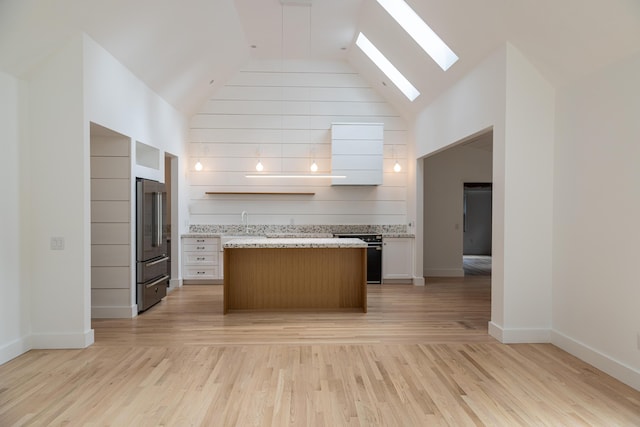 kitchen with light wood-type flooring, white cabinetry, range, and high end refrigerator