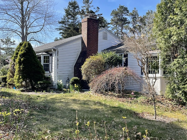 view of home's exterior featuring a lawn and a chimney