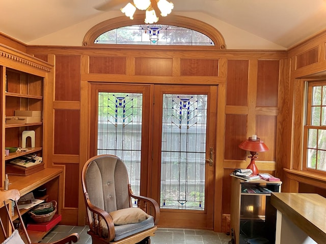 living area featuring a chandelier, wooden walls, and lofted ceiling