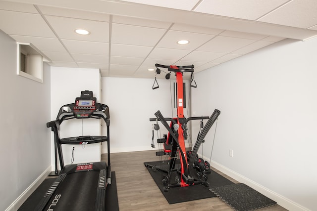 exercise area featuring recessed lighting, a drop ceiling, baseboards, and wood finished floors