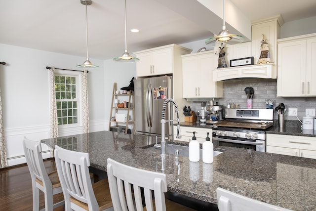 kitchen with hanging light fixtures, appliances with stainless steel finishes, and dark stone counters