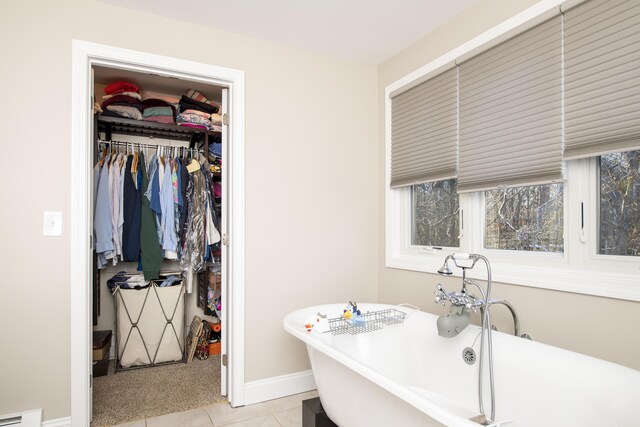 interior space with light tile patterned floors, a baseboard radiator, and baseboards