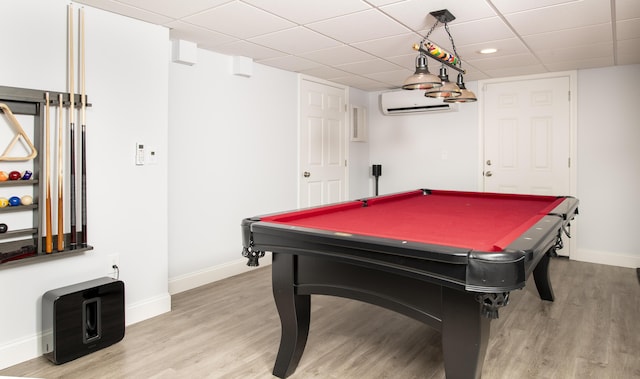 recreation room with light wood finished floors, billiards, baseboards, a wall mounted air conditioner, and a paneled ceiling