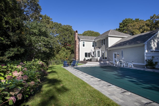 rear view of property featuring a wooden deck, a chimney, fence, and a lawn