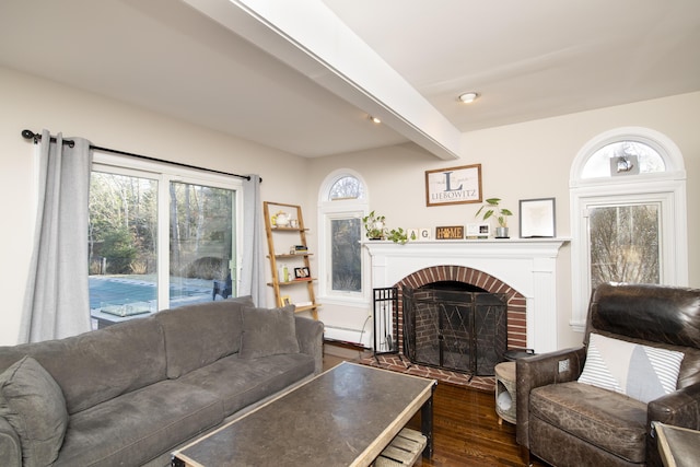 living area featuring a baseboard heating unit, dark wood-type flooring, beamed ceiling, and a wealth of natural light