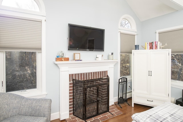 bedroom featuring lofted ceiling, dark wood-style floors, a fireplace, and baseboard heating