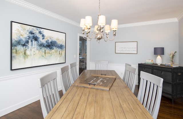 dining space featuring a wainscoted wall, dark wood-type flooring, an inviting chandelier, and crown molding