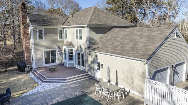 rear view of property with a chimney, a shingled roof, an attached garage, fence, and a wooden deck