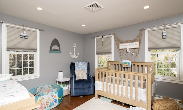 bedroom featuring recessed lighting, visible vents, dark wood finished floors, and a nursery area