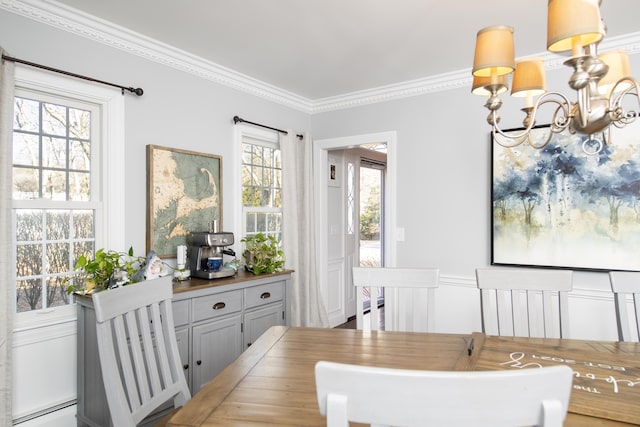 dining area featuring ornamental molding, baseboard heating, a notable chandelier, and wainscoting