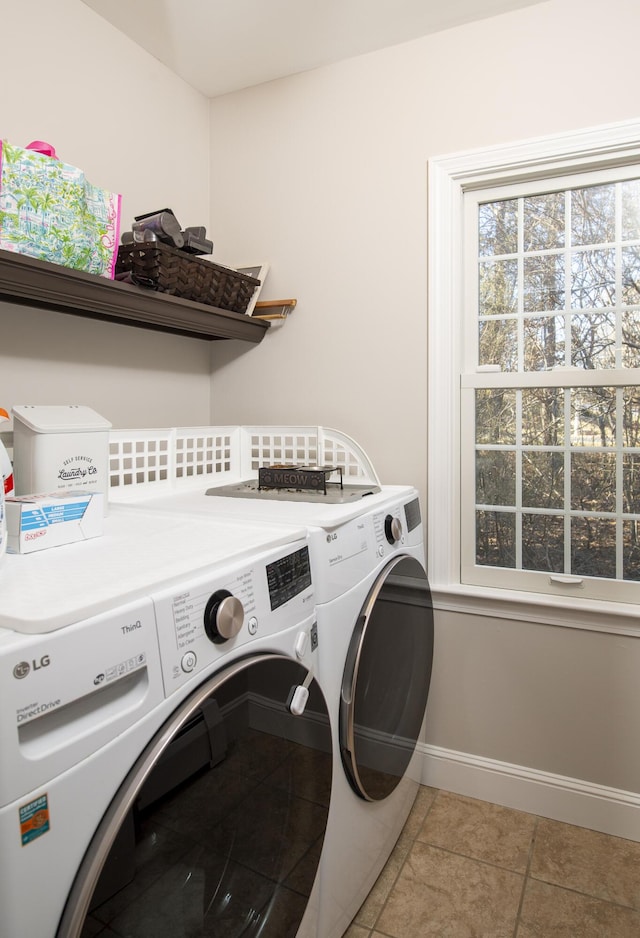 laundry room with light tile patterned floors, laundry area, washing machine and dryer, and baseboards