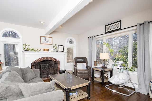 living room featuring a brick fireplace, dark wood-style flooring, and beamed ceiling