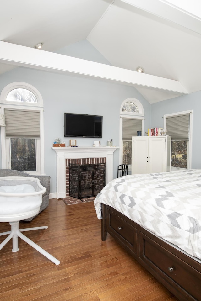 bedroom featuring lofted ceiling, light wood-style flooring, and a fireplace