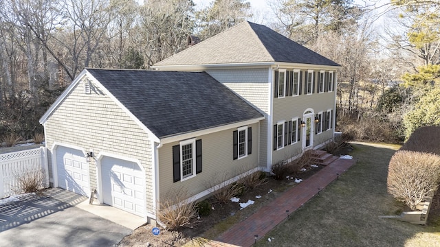 view of side of home with a garage, driveway, roof with shingles, and a chimney