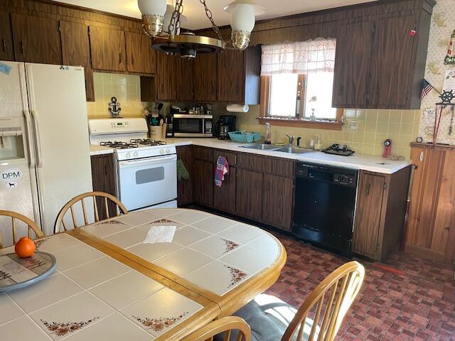 kitchen featuring a sink, backsplash, white appliances, an inviting chandelier, and light countertops