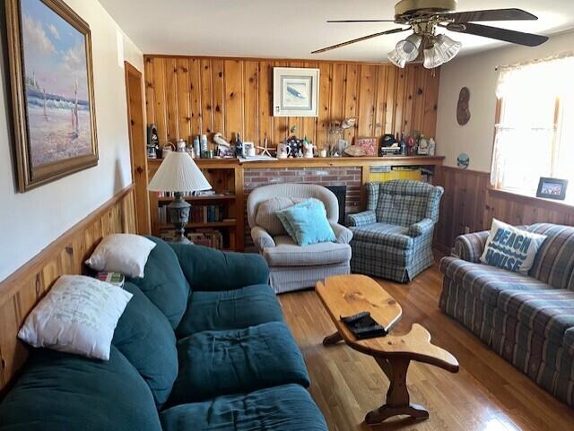 living room with a fireplace, wood finished floors, a wainscoted wall, and wood walls