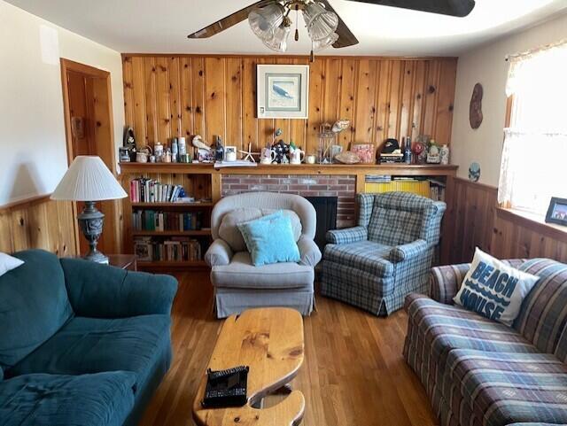 sitting room with wooden walls, wainscoting, a fireplace, and wood finished floors