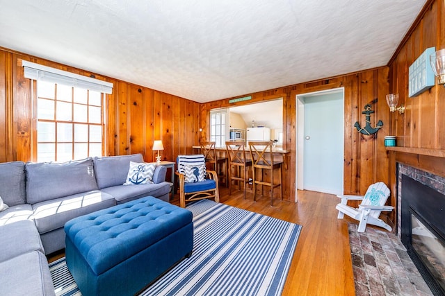 1006 Craigville Beach Rd Unit 4, Centerville, MA 02632 - living area featuring wood walls, healthy amount of natural light, a glass covered fireplace, a textured ceiling, and wood finished floors