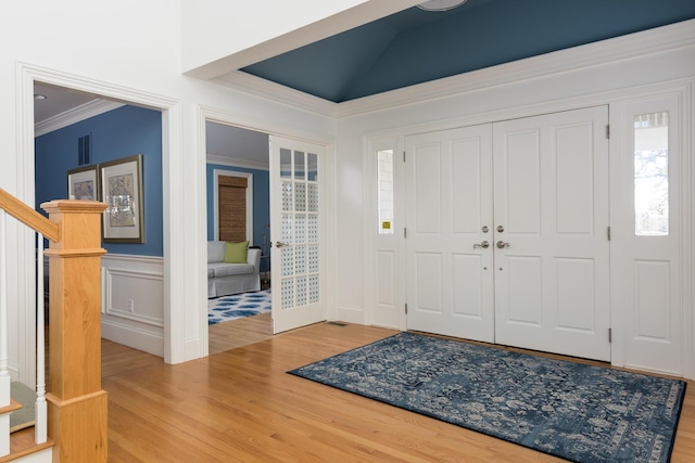 entrance foyer featuring visible vents, crown molding, stairs, french doors, and wood finished floors