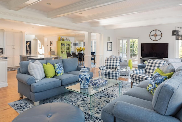 living area with decorative columns, beam ceiling, light wood-style flooring, and crown molding