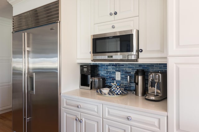 kitchen featuring light stone counters, decorative backsplash, appliances with stainless steel finishes, and white cabinets