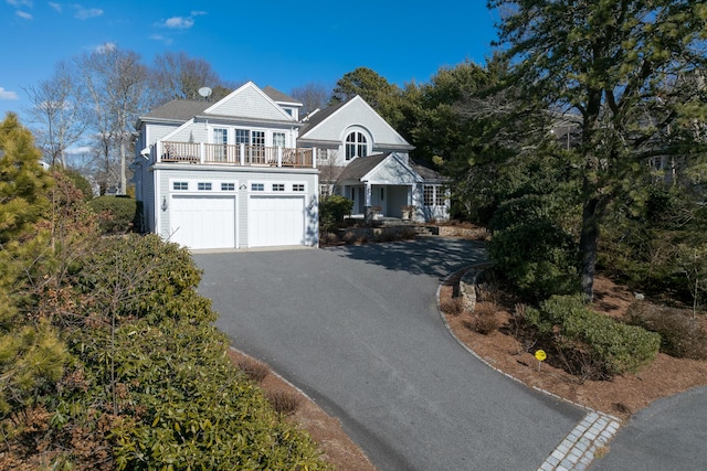 shingle-style home with aphalt driveway and a balcony