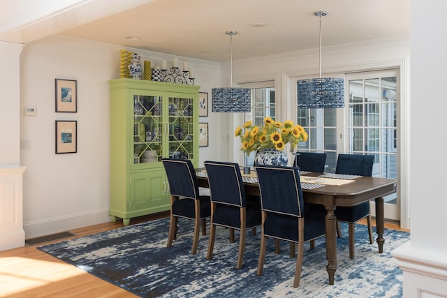 dining area featuring a healthy amount of sunlight, wood finished floors, and crown molding