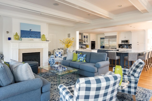 living room with light wood finished floors, visible vents, crown molding, a premium fireplace, and beam ceiling