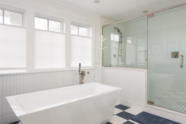 bathroom featuring a wainscoted wall, tile patterned floors, a freestanding tub, and a stall shower