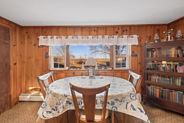 dining area with wooden walls, a wealth of natural light, and a baseboard heating unit