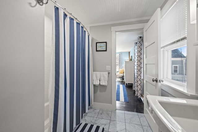 full bath featuring a shower with shower curtain, baseboards, marble finish floor, and ornamental molding