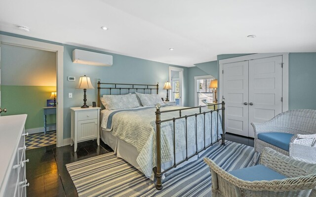 bedroom with dark wood-type flooring, baseboards, an AC wall unit, recessed lighting, and a closet