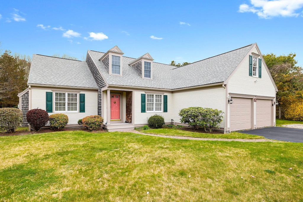 cape cod-style house featuring a garage and a front lawn