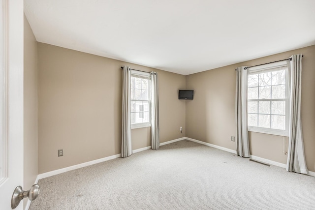 spare room with baseboards, visible vents, and light colored carpet