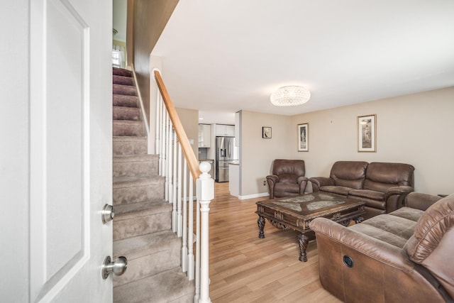 living room with light wood finished floors, stairs, and baseboards